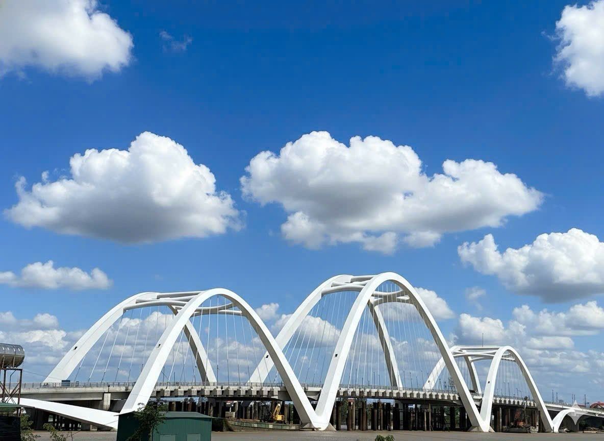 Cầu vòm thép sơn trắng trên nền trời, nhìn dọc mặt cầu